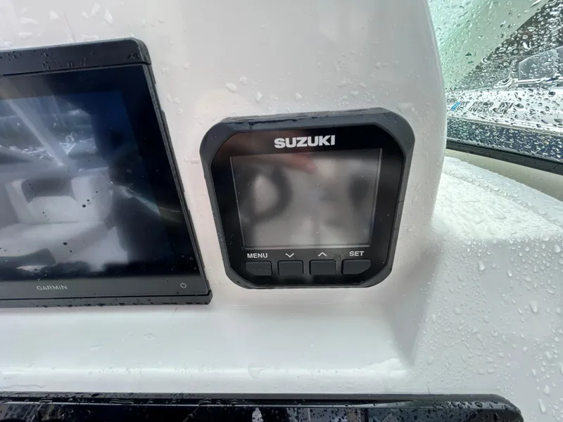 Slide: The Image of Suzuki display panel on 2024 Sailfish 226 DC boat dashboard, wet with raindrops. - 25