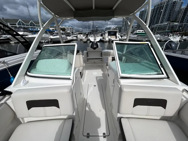 Slide: The Image of 2024 Sailfish 226 DC boat interior at marina, featuring white seating and open windshield. - 5