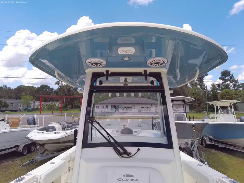 Slide: The Image of 2025 Cobia 265 Center Console boat with blue T-top, parked outdoors. - 10