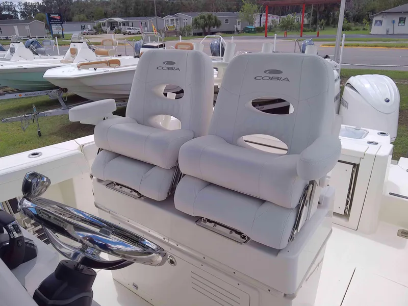Slide: The Image of 2025 Cobia 265 Center Console boat with dual cushioned seats and steering wheel. - 11