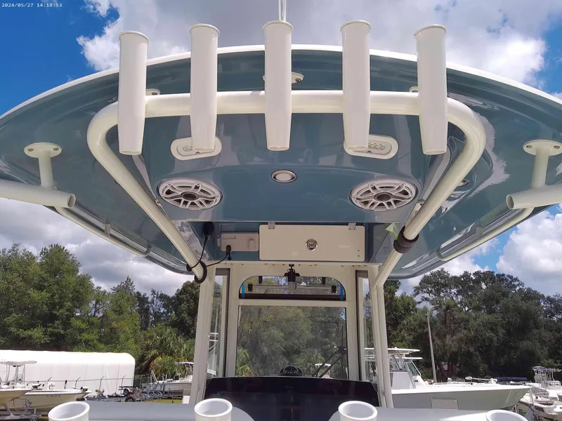Slide: The Image of 2025 Cobia 265 Center Console boat with rod holders and speakers under blue canopy. - 5