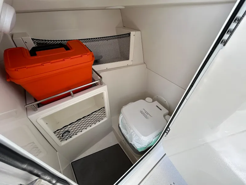 Slide: The Image of 2024 Sailfish 226 DC boat interior with storage and portable toilet. - 13