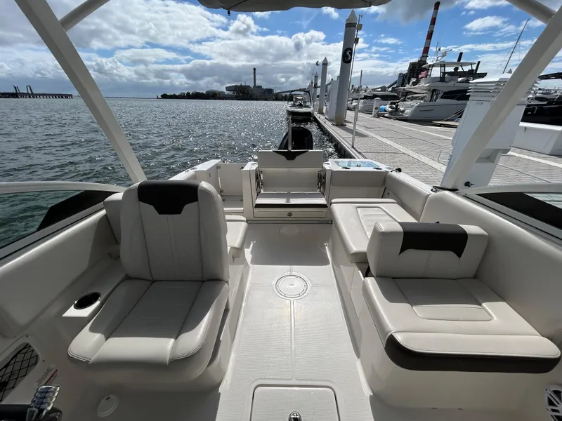 Slide: The Image of 2024 Sailfish 226 DC boat interior with plush seating, docked by the waterfront. - 15