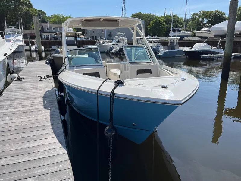 Slide: The Image of 2024 Sailfish 226 DC boat docked in a marina, featuring a sleek blue and white design. - 4