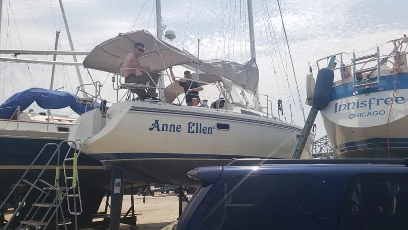 The Image of 1994 Catalina 36 sailboat "Anne Ellen" on land, with people onboard, near other boats. - 0