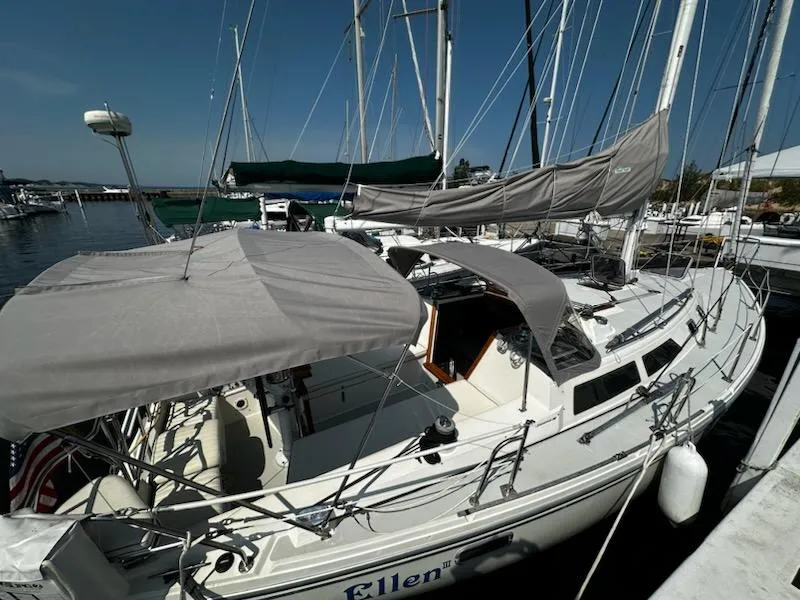 Slide: The Image of 1994 Catalina 36 sailboat docked at marina, featuring covered cockpit and sails. - 6