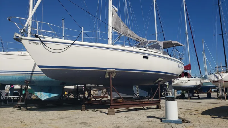Slide: The Image of 1994 Catalina 36 sailboat on dry dock, white hull, blue stripe, clear sky background. - 8