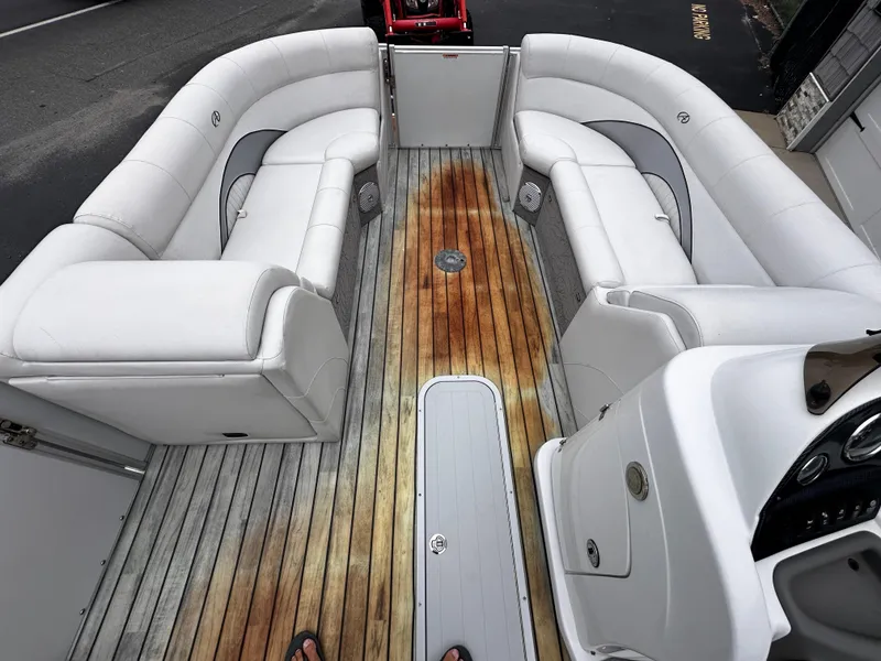 Slide: The Image of 2014 Avalon Catalina Quad Lounge boat interior with white seating and wooden deck. - 23