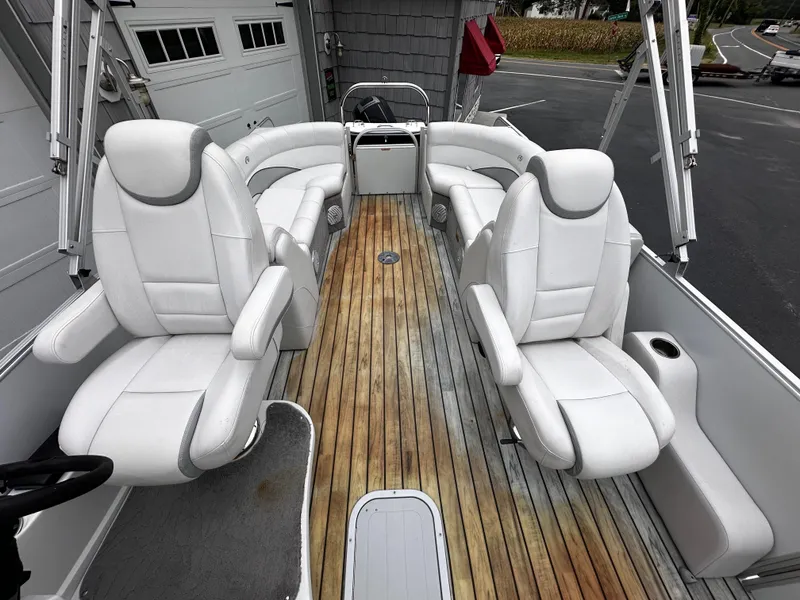Slide: The Image of 2014 Avalon Catalina Quad Lounge boat interior with white seating and wooden deck. - 24