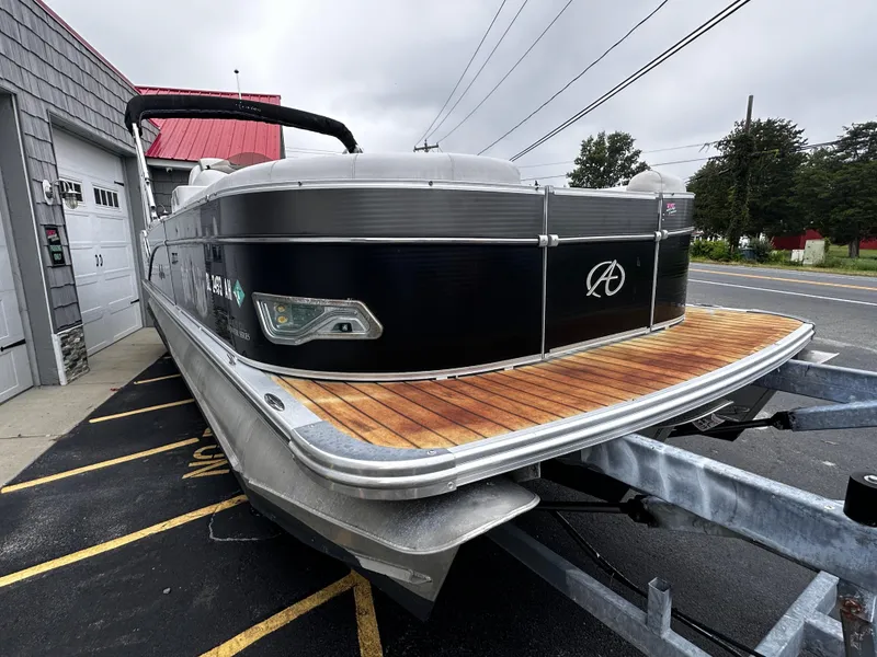 Slide: The Image of 2014 Avalon Catalina Quad Lounge 24' Triple Toon boat on trailer, parked near a building. - 7