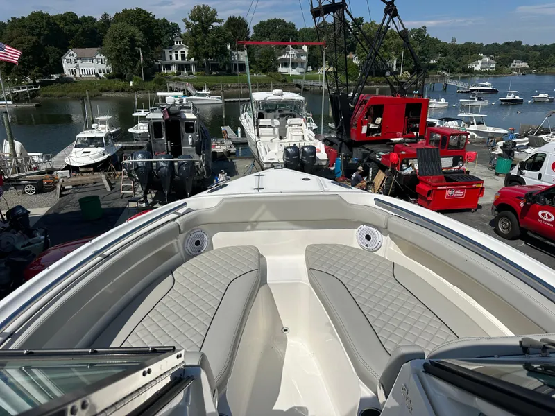 Slide: The Image of 2025 Pursuit DC 266 Dual Console boat docked at a marina with scenic waterfront view. - 3