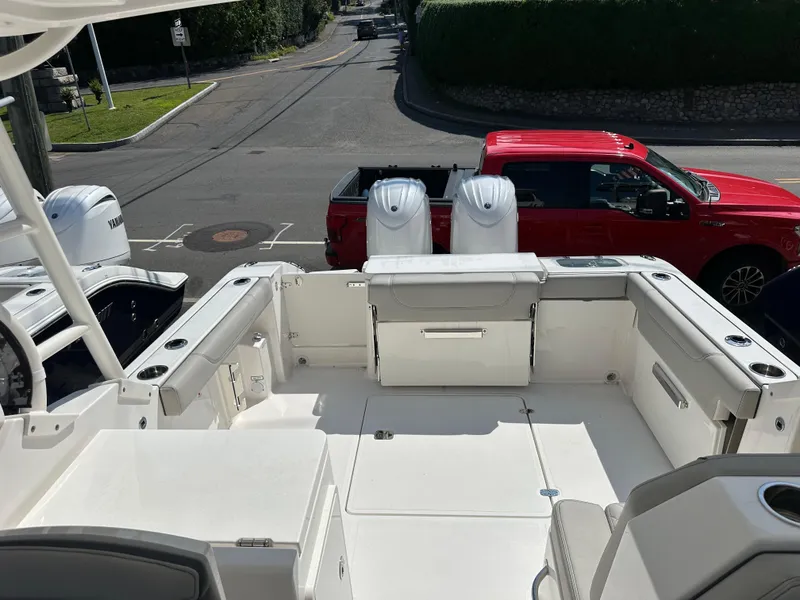 Slide: The Image of 2025 Pursuit DC 266 Dual Console boat interior with dual engines, parked near a red vehicle. - 4