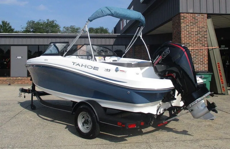 Slide: The Image of 2023 Tahoe 185 S boat with outboard motor, parked on a trailer outside a building. - 2