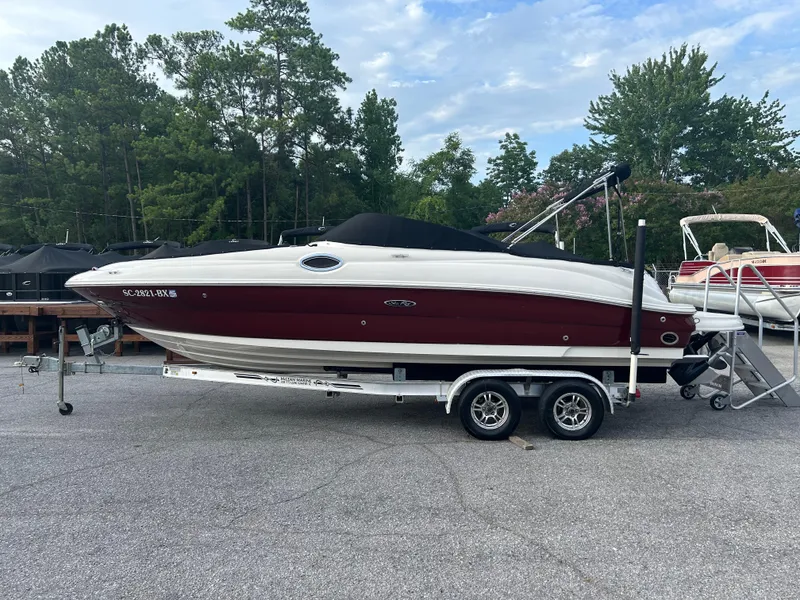 Slide: The Image of 2007 Sea Ray 240 Sundeck boat on trailer, parked outdoors with trees in background. - 3