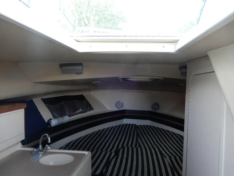 Slide: The Image of Interior cabin of a 1999 Pursuit 2860 Denali boat with striped bedding and a small sink. - 4