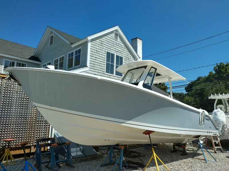 Slide: The Image of 2025 Pursuit S 288 Sport boat on stands near a house under clear blue sky. - 11
