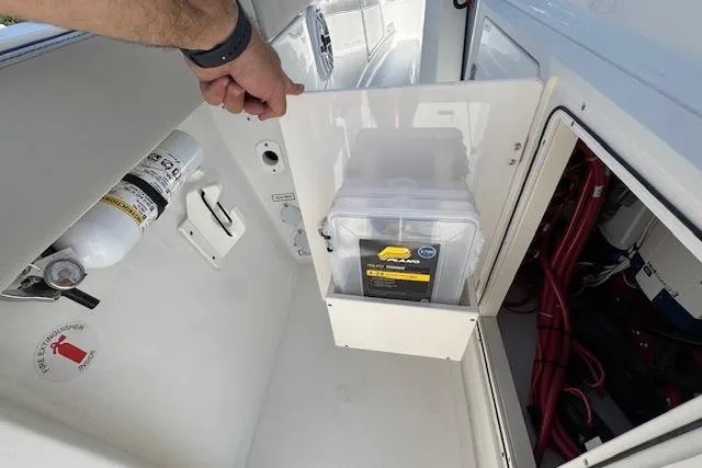 Slide: The Image of 2026 Pursuit S 328 Sport boat storage compartment with fire extinguisher and safety equipment. - 33
