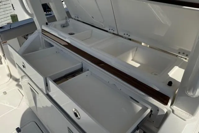 Slide: The Image of 2026 Pursuit S 328 Sport boat interior with open storage compartments and sink. - 6