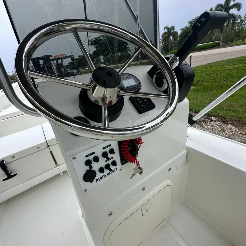 Slide: The Image of 2024 Rigid Boats 17' Sport steering console with controls and key. - 11