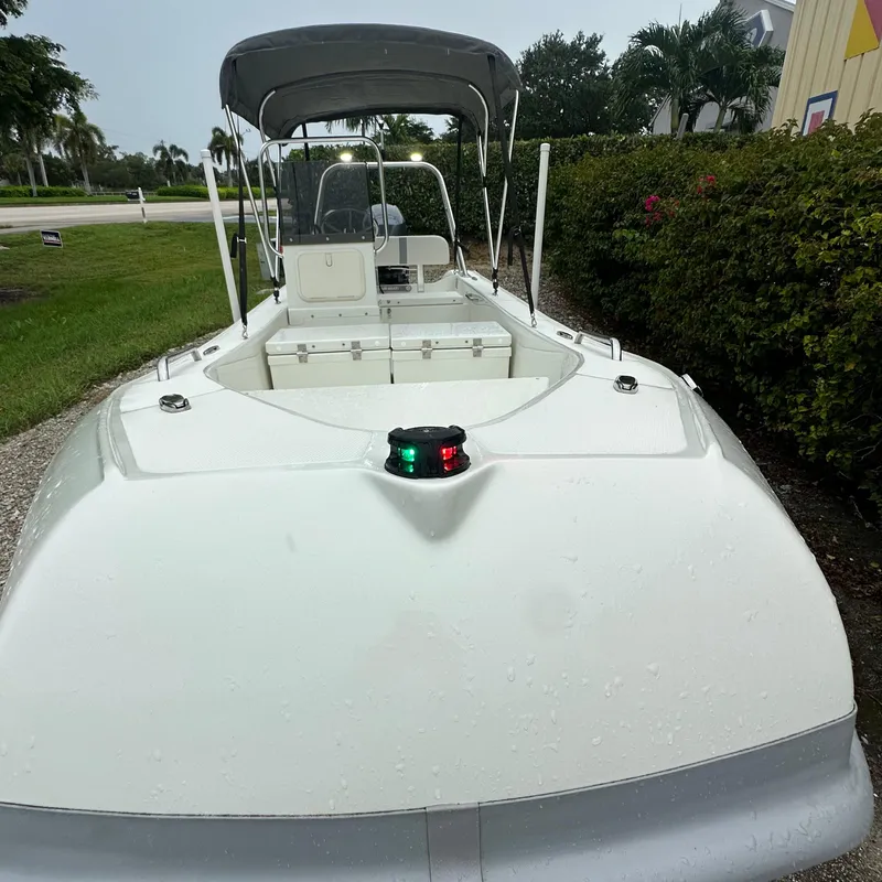 Slide: The Image of 2024 Rigid Boats 17' Sport with canopy, parked outdoors. - 17