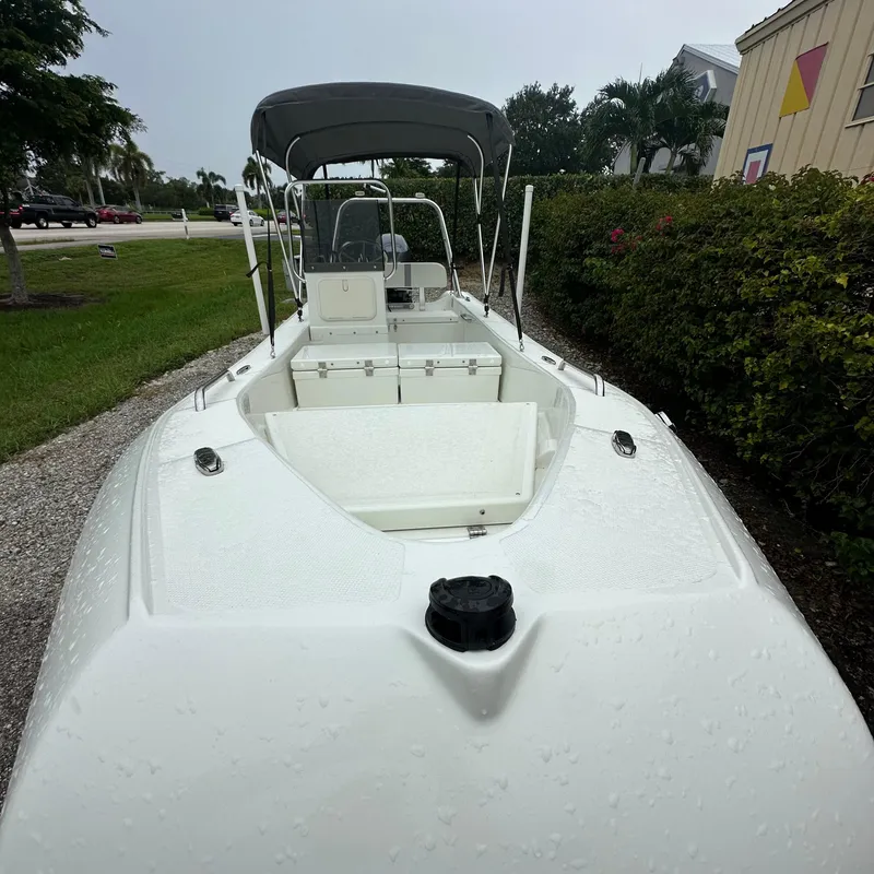 Slide: The Image of 2024 Rigid Boats 17' Sport, white deck, parked outdoors, with canopy and seating. - 2