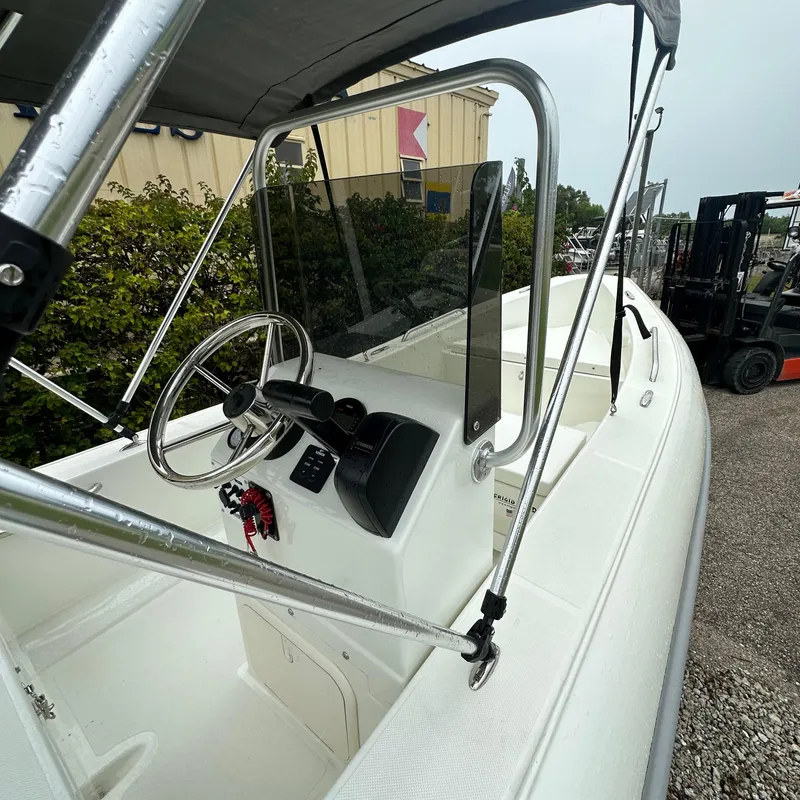 Slide: The Image of 2024 Rigid Boats 17' Sport, white interior, steering console, outdoor display. - 5