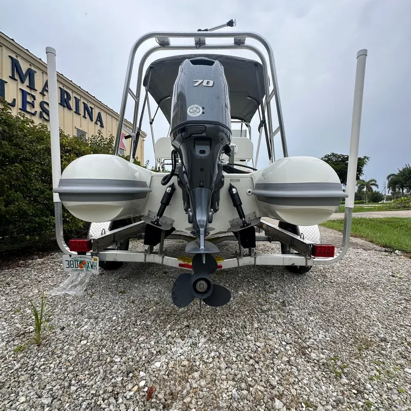 Slide: The Image of 2024 Rigid Boats 17' Sport with outboard motor, parked on gravel. - 9