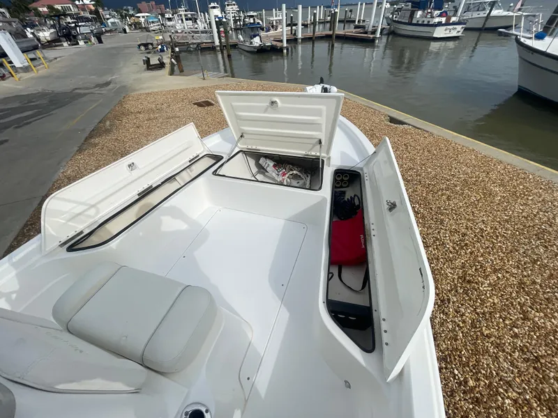 Slide: The Image of 2005 ShearWater 2200 boat with open storage compartments at a marina. - 20