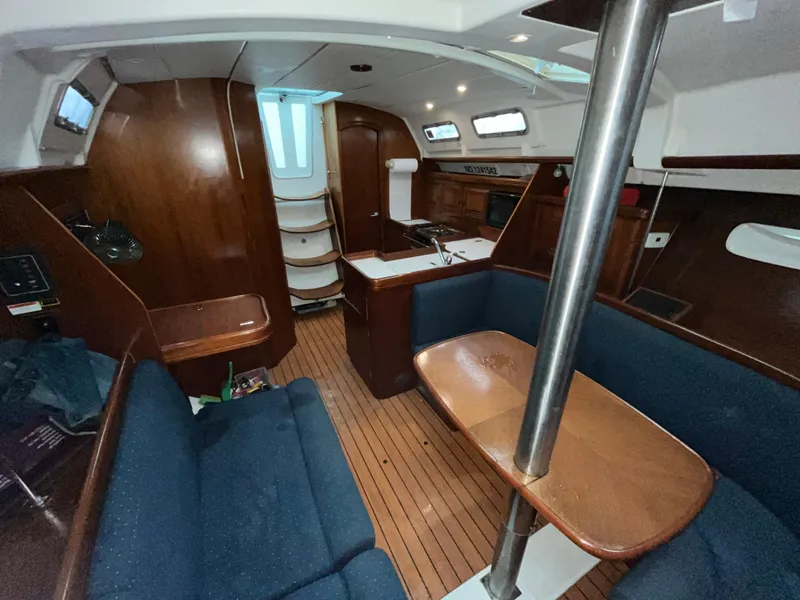 Slide: The Image of Interior of 2005 Beneteau Oceanis Clipper 373 sailboat, featuring wood finish and blue seating. - 8