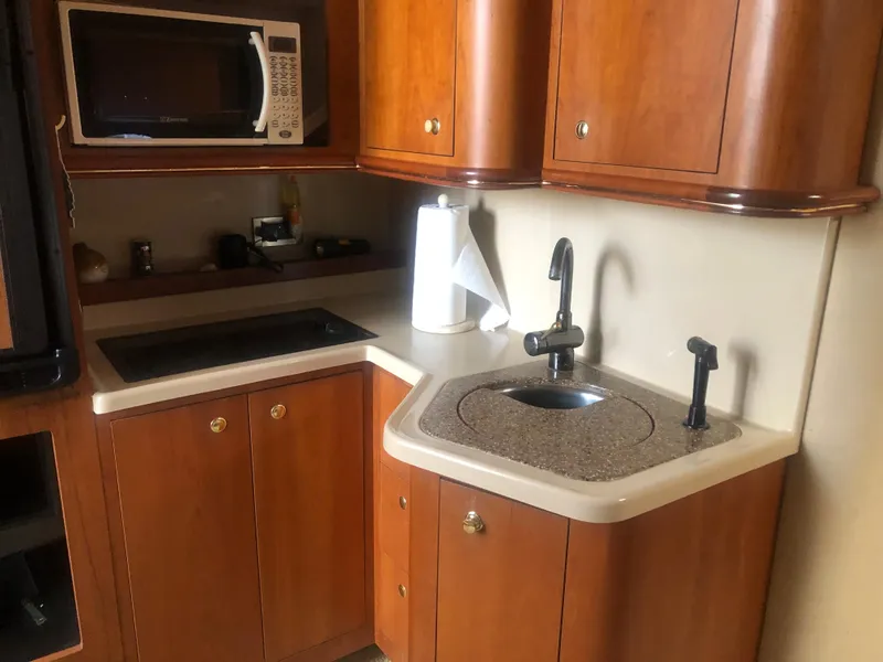 Slide: The Image of 2001 Cruisers Yachts 3672 Express kitchen with microwave, sink, and wooden cabinetry. - 17