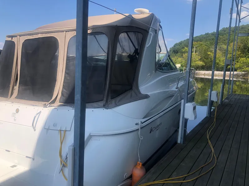 Slide: The Image of 2001 Cruisers Yachts 3672 Express docked, featuring a covered cabin and scenic background. - 5