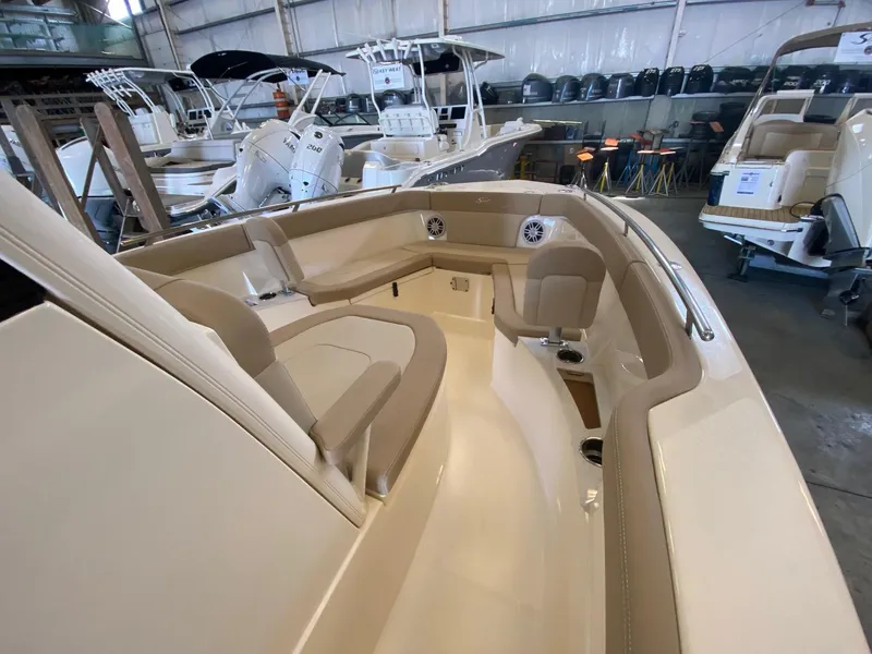 Slide: The Image of 2025 Scout 240 XSF boat interior with beige seating in a showroom. - 14