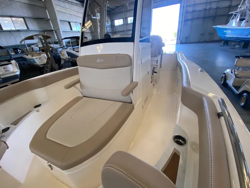 Slide: The Image of 2025 Scout 240 XSF boat interior with beige seating in a showroom. - 16