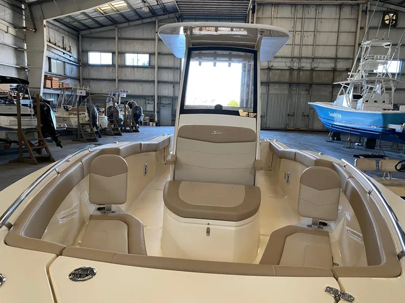 Slide: The Image of 2025 Scout 240 XSF boat interior with beige seating in a spacious warehouse. - 6