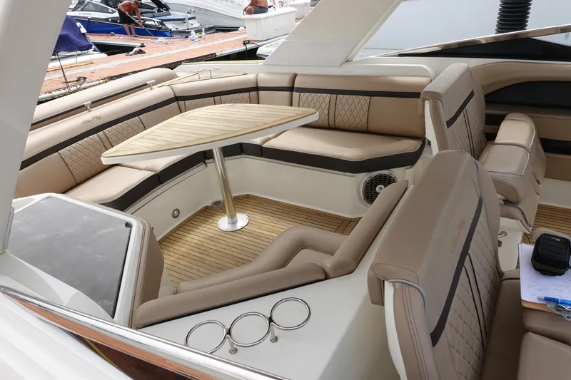 Slide: The Image of 2017 Sea Ray SLX 310 boat interior with beige seating and wooden table. - 14