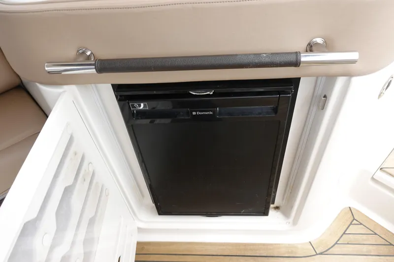 Slide: The Image of 2017 Sea Ray SLX 310 boat interior with Dometic mini fridge and beige seating. - 17