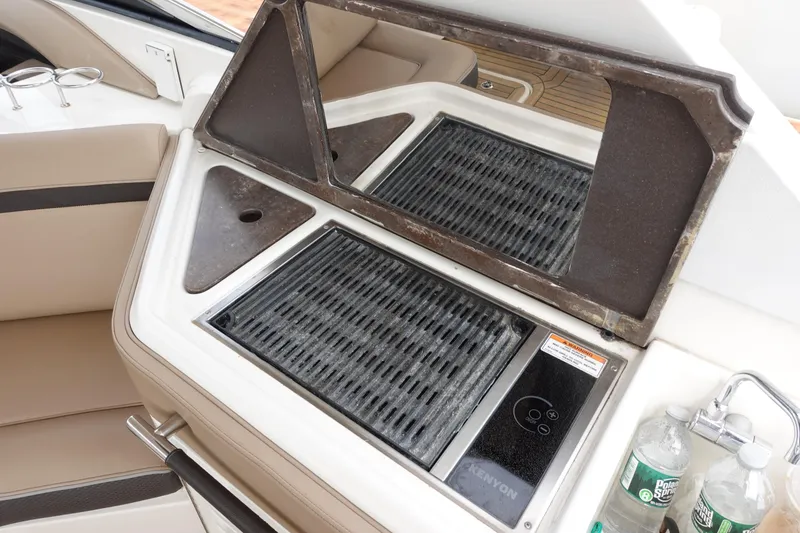 Slide: The Image of Outdoor grill on 2017 Sea Ray SLX 310 boat with water bottles nearby. - 18