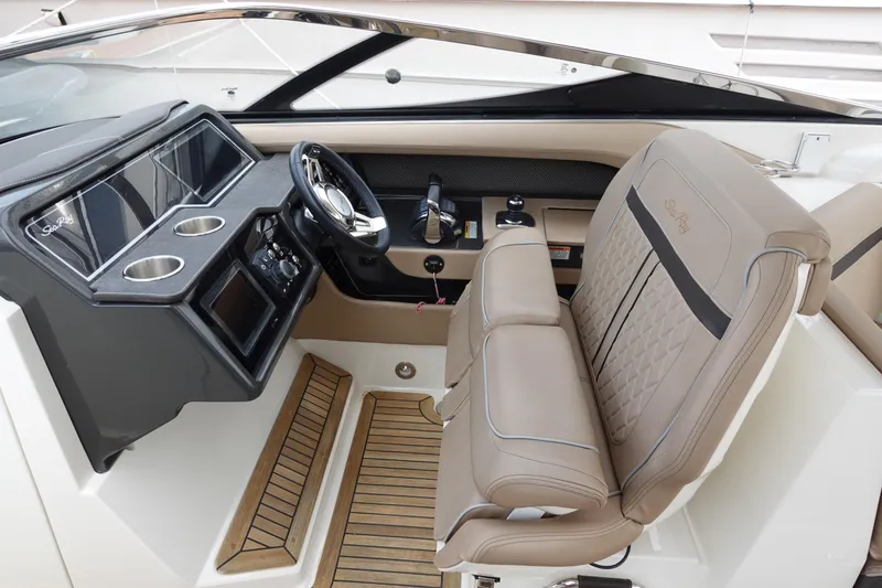 Slide: The Image of 2017 Sea Ray SLX 310 boat interior with helm, steering wheel, and beige seating. - 4