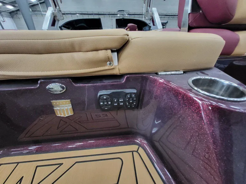 Slide: The Image of 2022 MasterCraft XT23 boat interior with maroon finish, beige seating, and control panel. - 10