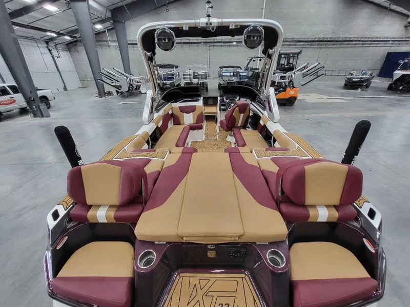 Slide: The Image of 2022 MasterCraft XT23 boat interior with maroon and tan seating in a spacious warehouse. - 11