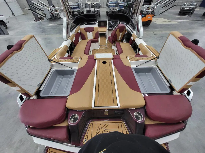Slide: The Image of 2022 MasterCraft XT23 boat interior with maroon and tan seating, open storage compartments. - 12