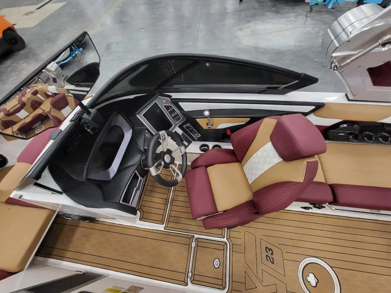 Slide: The Image of 2022 MasterCraft XT23 boat interior with maroon and tan seating, modern dashboard, and steering wheel. - 19
