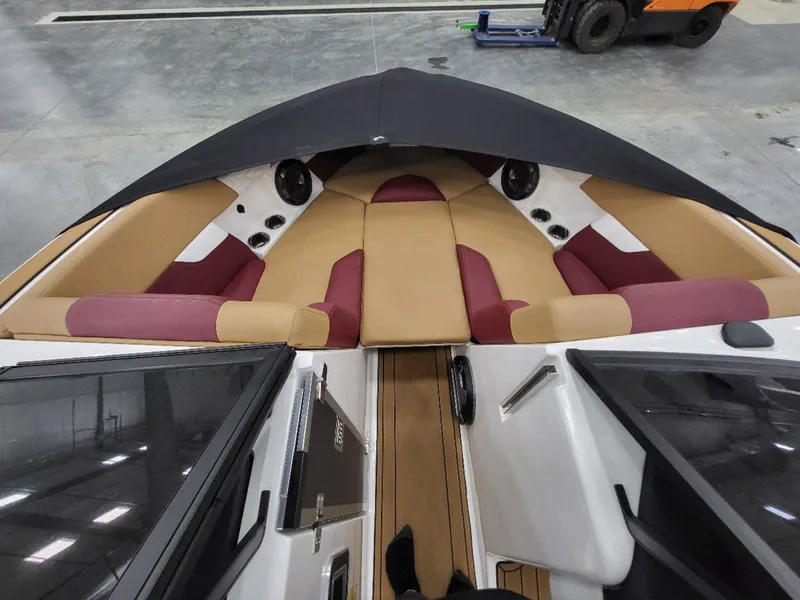Slide: The Image of 2022 MasterCraft XT23 boat interior with tan and maroon seating, docked indoors. - 21