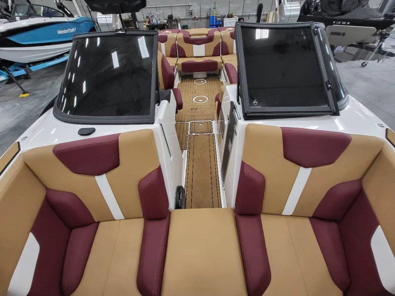Slide: The Image of 2022 MasterCraft XT23 boat interior with tan and burgundy seating. - 23