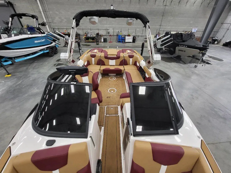 Slide: The Image of 2022 MasterCraft XT23 boat interior with tan and maroon seating in a showroom. - 24