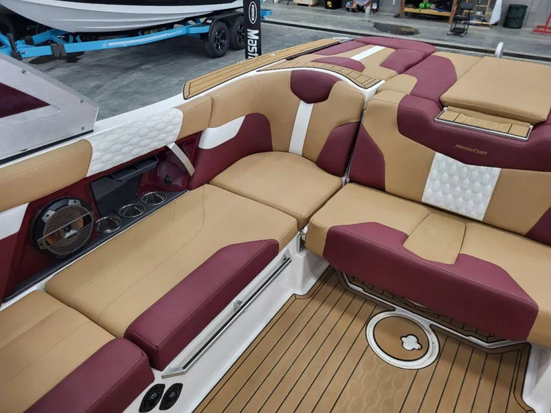 Slide: The Image of 2022 MasterCraft XT23 boat interior with tan and maroon seating, wood-style flooring. - 25