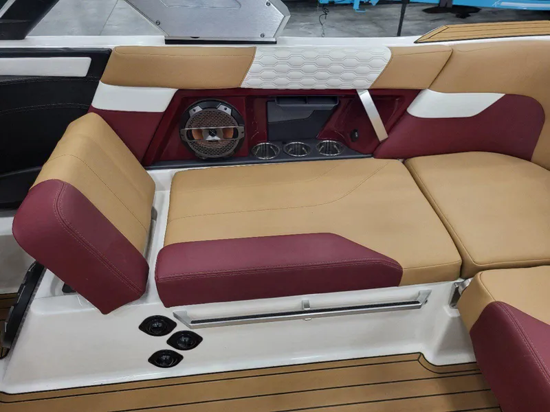Slide: The Image of 2022 MasterCraft XT23 interior with tan and maroon seating, speaker, and cup holders. - 27