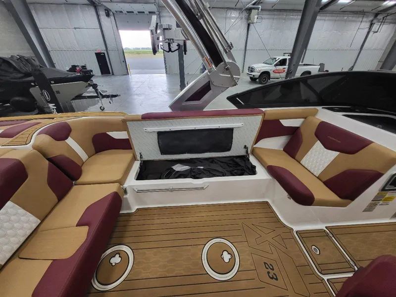 Slide: The Image of 2022 MasterCraft XT23 boat interior with maroon and tan seating in a garage. - 29