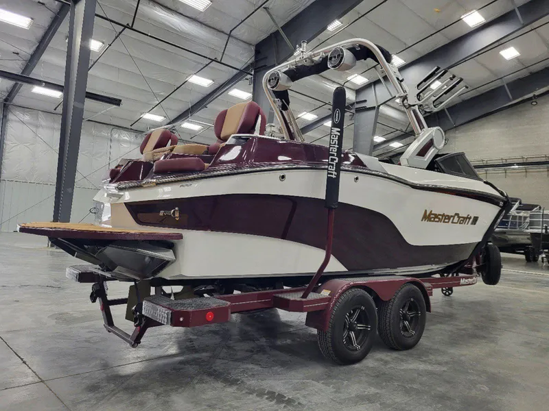 Slide: The Image of 2022 MasterCraft XT23 boat in a warehouse, maroon and white design on trailer. - 3