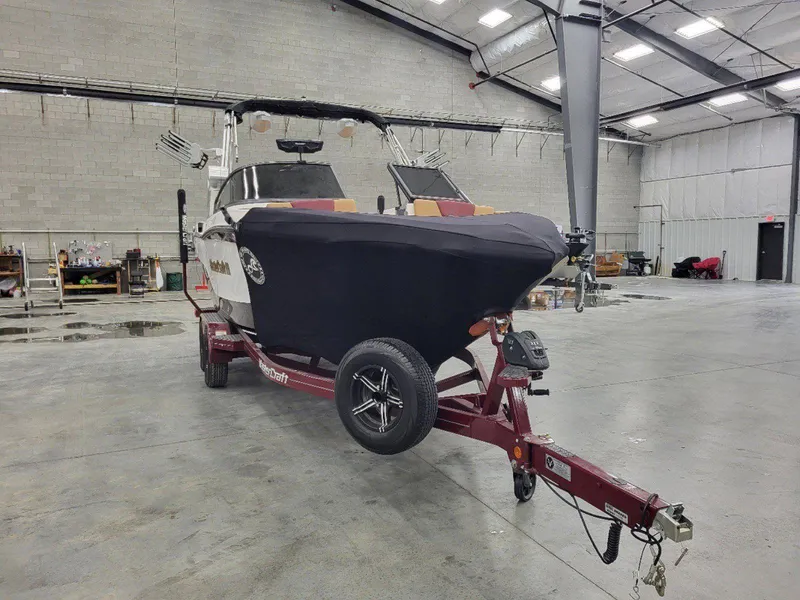 Slide: The Image of 2022 MasterCraft XT23 boat on trailer in spacious indoor storage facility. - 30